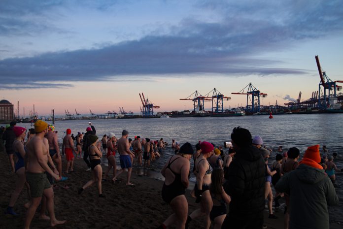 Eine große Gruppe an Menschen steht in Badekleidung am Elbstrand