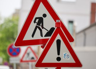 Bauarbeiten an der Hamburger Elbgaustraße bis 2027 Zwei Baustellenschilder stehen im Vordergrund. Im Hintergrund ist verschwommmen eine Straße zu sehen.