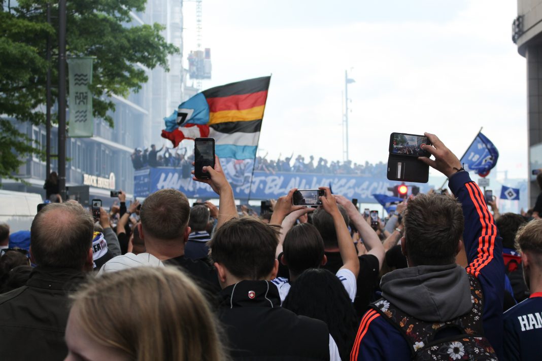 HSV-Fans filmen Spielerbus im Hintergrund