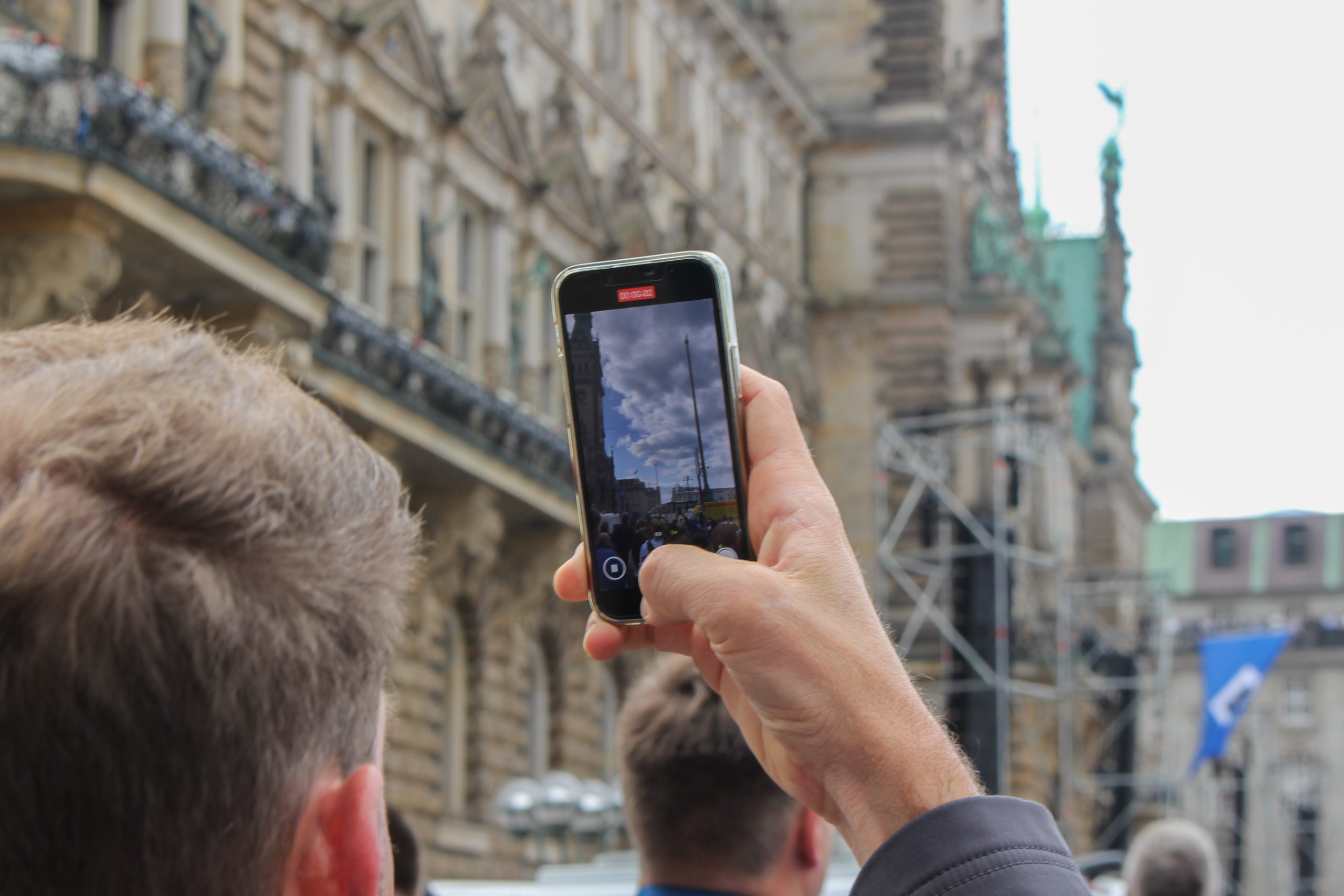 Mann filmt Rathaus mit Handy