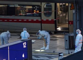 Mehrere Personen bei Messerattacke verletzt Ermittler in Schutzanzügen sichern Spuren an einem abgesperrten Bahnsteig vor einem ICE-Zug in einem Bahnhof. Der Bereich ist mit rot-weißem Band abgesperrt.