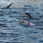 Straßensperrungen zum Ironman Fünf Personen mit Schwimmkappen und Schwimmbrillen schwimmen nebeneinander in der Alster.