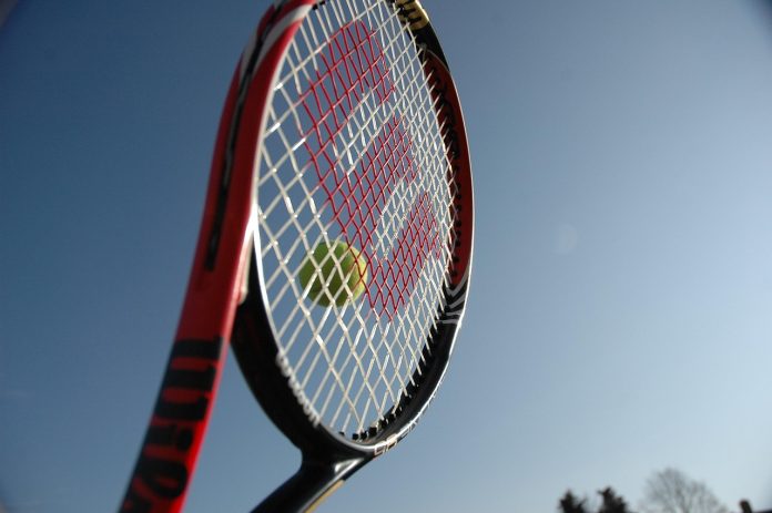 Ein Tennisschläger mit Ball vor blauem Himmel