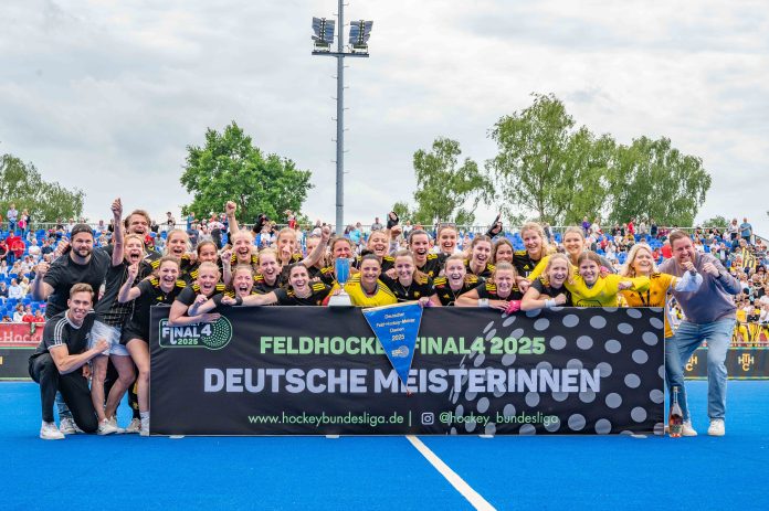 Frauen im Trikot stehen hinter einem Banner,