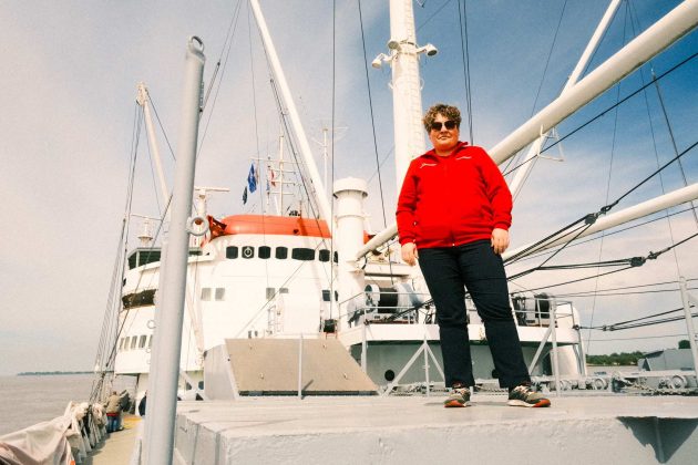 Cynthia Wolter steht auf dem Deck der Cap San Diego. Im Hintergrund sieht man mittig die Brücke.