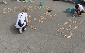 Zwei Menschen legen aus Zigaretten den Schriftzug "Defend the Deep".