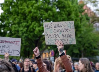Nehmt euch die Nacht zurück! Demonstrierende bei Take back the Night halten Fäuste und Plakate in die Luft