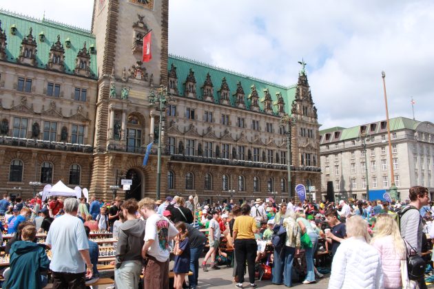 Viele Kinder und Erwachsene stehen vor dem Rathaus und spielen Schach.