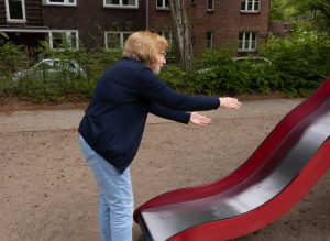 Eine Frau steht mit ausgebreitteen Armen an einer Rutsche.