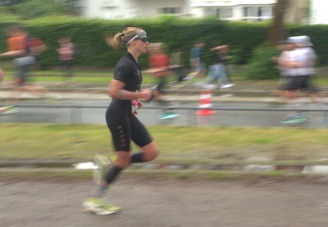 Triathletin Konczalla läuft in Richtung der rechten Bildseite. Der Hintergrund ist verschwommen.