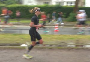 Triathletin Konczalla läuft in Richtung der rechten Bildseite. Der Hintergrund ist verschwommen.