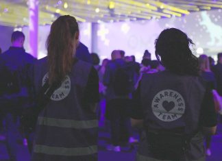 Awareness zwischen Menschenmassen und Marketingmoguln Zwei Mitarbeitende des OMR Awareness-Teams stehen mit dem Rücken zur Kamera. Sie schauen auf eine Menschenmasse, im Hintergrund ist eine Bühne zu sehen.