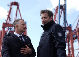 Zollbilanz 2024 – Einnahmen sind letztes Jahr gesunken Lars Klingbeil und Armin Rolfink stehen an Bord eines Schiffes vor zwei Kränen im Hamburger Hafen.
