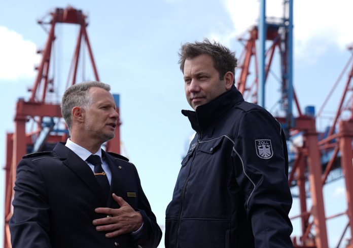 Zoll stellt Jahresbilanz 2024 vor Lars Klingbeil und Armin Rolfink stehen an Bord eines Schiffes vor zwei Kränen im Hamburger Hafen.