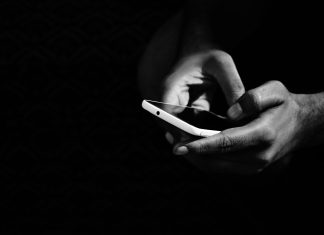 Mehr als zwei Drittel meiden Nachrichten aus Selbstschutz Handy in einer Hand in schwarz-weiß.