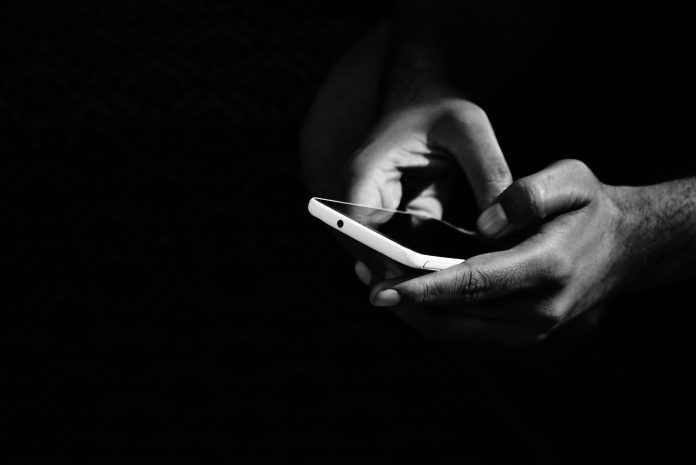 Handy in einer Hand in schwarz-weiß.