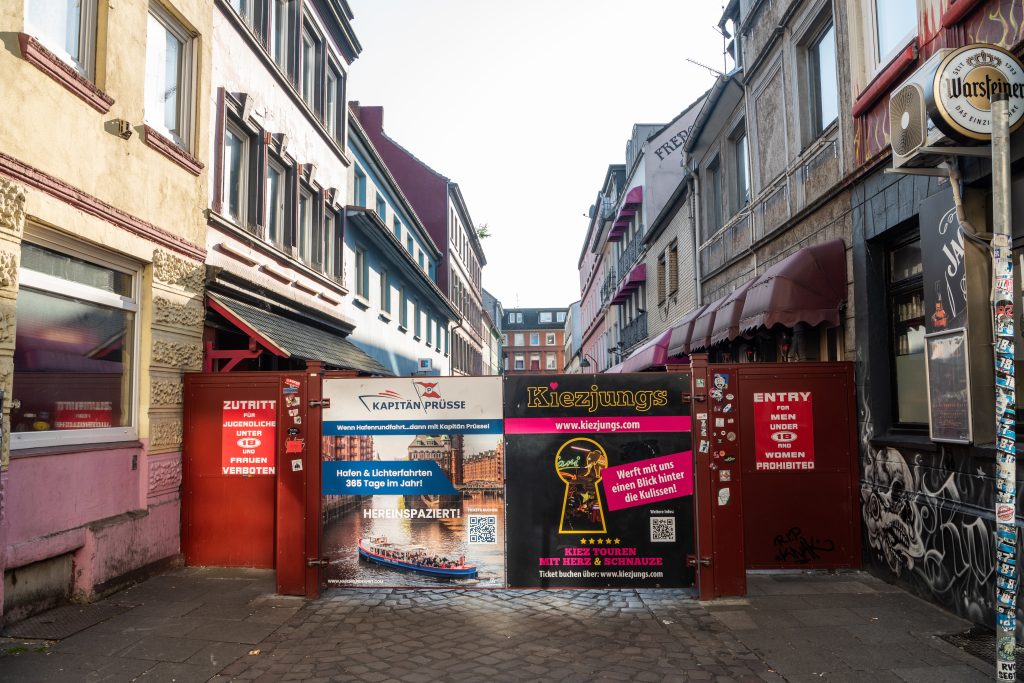 Ein Eisentor versperrt den Eingang zur Herbertstraße. Daran hängen Schilder, zum Beispiel mit der Aufschrift „Frauen verboten".