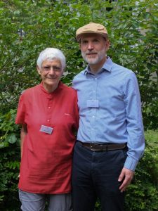 Ältere Frau und älterer Mann vor einer grünen Hecke.