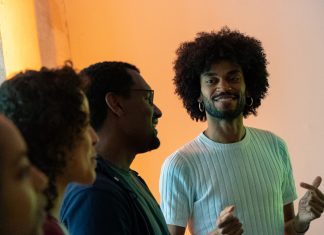 „Mehrstimmm.Ich“ – Ein Gesangsworkshop, der Schwarze Stimmen hörbar macht FAYIM schaut stolz auf drei Workshop-Teilnehmer*innen und lächelt dabei. Die Teilnehmer*innen singen.