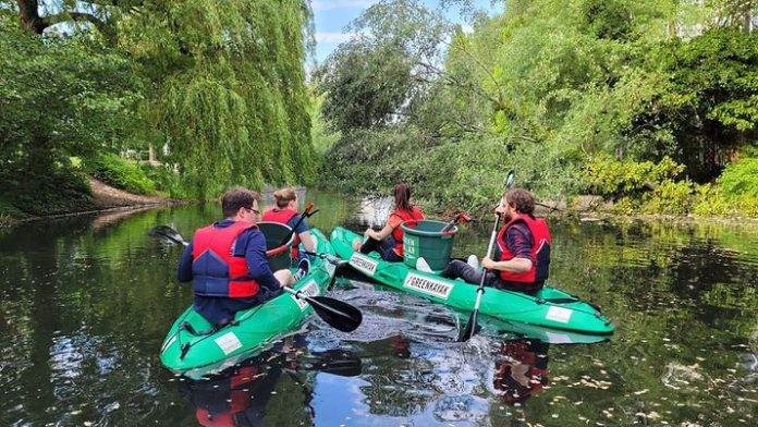 Zwei Green-Kayaks auf dem Wasser mit müllsammelnden Menschen.
