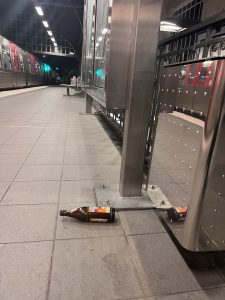 Eine leere Spezi-Flasche liegt quer auf dem leeren Gehweg am U-Bahnhof.