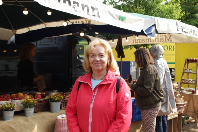Anne Faika steht vor einem Obststand auf ihrem Bio-Wochenmarkt