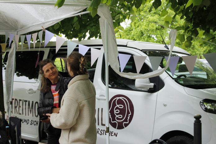 Katja Kaiser steht vor ihrem Streitmobil und unterhält sich mit einer anderen Person.