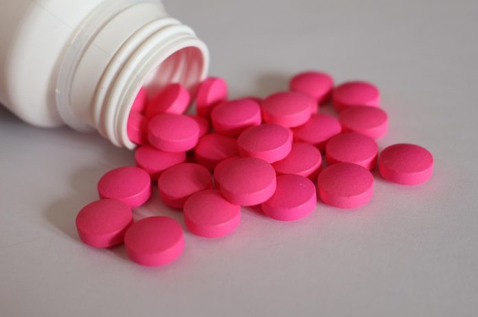 Eine weiße Pillendose aus der pinke Tabletten fallen als Symbolbild fürs Drug-Checking.