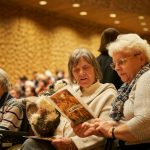 Klangzeitkonzert: Musik gegen das Vergessen Mehrere ältere Frauen sitzen in einem Konzertsaal. Zwei ältere Frauen mit weißen und grauen Haaren halten ein Liederheft in ihren Händen. Sie besuchen ein Klangzeitkonzert in der Elbphilharmonie.