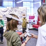 Kreativ Technik und KI entdecken Ein Kind hat eine Virtual-Reality-Brille auf dem Kopf und einen Controller in der Hand. Grund dafür ist die Auftaktveranstaltung der Code Week Hamburg in der Hamburger Bücherhalle.