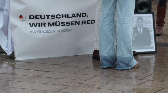 WMR2610_Kirk Die Hosenbeine einer Frau in Jeans vor einem Tisch mit einem Banner mit der Aufschrift