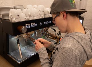 Mittendrin statt am Rande der Gesellschaft Eine Frau mit einer Kappe bedient eine Kaffeemaschine.