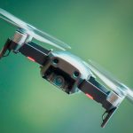 Polizei setzt erstmals Drohnen an Halloween ein Eine Drohne die vor einem grünen Hiintergrund schräg durch die Luft fliegt.