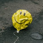 Wie zufrieden ist Hamburg wirklich? Ein zerknitterter gelber Luftballon mit einem Smilely liegt auf der Straße