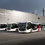 Verkehrsbetriebe Hamburg-Holstein testen Doppeldeckerbus Elektrobusse von vhh.mobility auf dem Betriebshof Bergedorf stehen vor einer gruaen Halle mit der Aufschrift "elexitxy". Die Busflotte wird aktuell durch eine Testphase eines Doppeldeckerbusses erweitert.