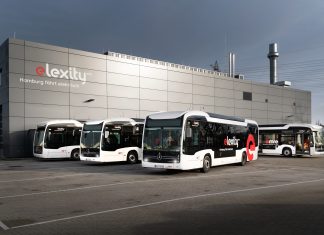 Verkehrsbetriebe Hamburg-Holstein testen Doppeldeckerbus Elektrobusse von vhh.mobility auf dem Betriebshof Bergedorf stehen vor einer gruaen Halle mit der Aufschrift "elexitxy". Die Busflotte wird aktuell durch eine Testphase eines Doppeldeckerbusses erweitert.