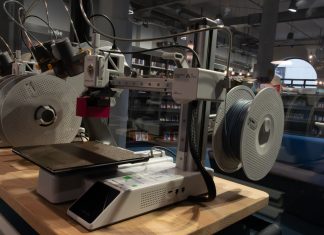 3D-Druck-Führerschein: Quietscheentchen und Brettspielpuppen Ein 3D-Drucker steht auf einem Tisch vor einer Glaswand.