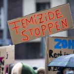 Häusliche Gewalt in Hamburg nimmt zu: Die Opfer sind Frauen Ein braunes Schild wird über den Köpfen von Menschen hochgehalten. darauf steht der orangefarbener Satz "Femizide stoppen"