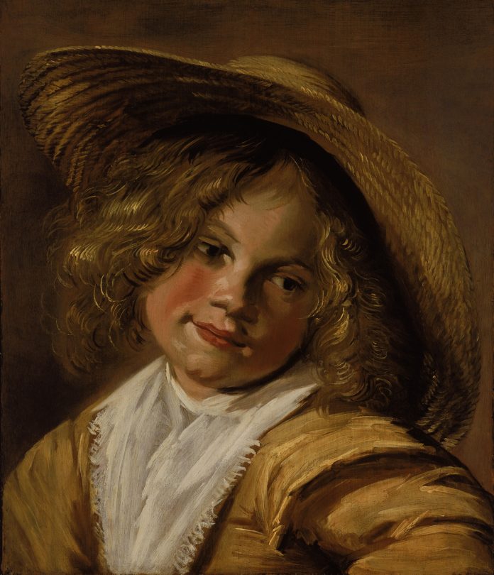 blondes Mädchen mit Strohhut auf dem Kopf schaut zur Seite