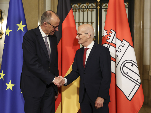 Antrittsbesuch Bundeskanzler Friedrich Merz in Hamburg Der Bundeskanler Friedrich Merz und der Bürgermeister Peter Tschentscher recihen sich die Hände. Im Hintergrund sind Flaggen aufgestellt.