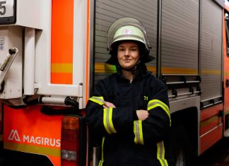 Feuerwehrfrau Nora Tenbusch Feuerwehrfrau Nora Tenbusch steht vor einem Einsatzwagen der Feuerwehr. Sie trägt die Schutzkleidung der Feuerwehr und hat einen Helm auf dem kopf. Sie schaut in die Kamera und hat ihre Arme verschränkt.