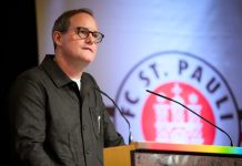 FC St. Pauli: Göttlich kündigt Stadionausbau an Der Präsident des FC St. Pauli, Oke Göttlich, steht an einem Rednerpult. Hinter ihm ist das Logo des Vereins zu sehen.