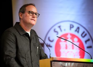 FC St. Pauli: Göttlich kündigt Stadionausbau an Der Präsident des FC St. Pauli, Oke Göttlich, steht an einem Rednerpult. Hinter ihm ist das Logo des Vereins zu sehen.