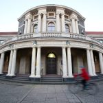 Klimaneutralität 2045: Mehr Maßnahmen notwendig Eine Frau fährt mit einem Fahrrad an dem Hauptgebäude der Universität Hamburg vorbei.