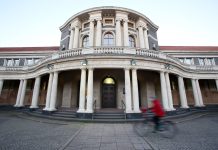 Klimaneutralität 2045: Mehr Maßnahmen notwendig Eine Frau fährt mit einem Fahrrad an dem Hauptgebäude der Universität Hamburg vorbei.