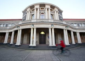 Klimaneutralität 2045: Mehr Maßnahmen notwendig Eine Frau fährt mit einem Fahrrad an dem Hauptgebäude der Universität Hamburg vorbei.
