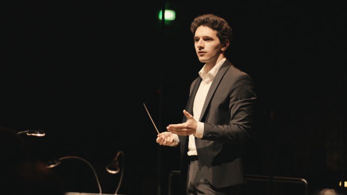 Emanuel Meshvinski leitet das jüdische Kammerorchester. Ein Dirigent steht auf der Bühne.