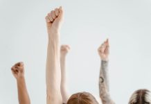 Orange Day 2025: Diese Aktionen finden in Hamburg statt Mehrere Menschen halten ihren gestreckten Arm in die Luft und machen eine Faust.