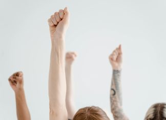 Orange Day 2025: Diese Aktionen finden in Hamburg statt Mehrere Menschen halten ihren gestreckten Arm in die Luft und machen eine Faust.