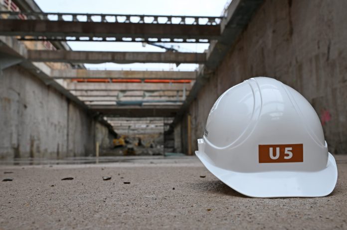 Baugrube der künftigen U5-Haltestelle «City Nord» Ein weißer Helm mit der Aufschrift U5 liegt in einer Baugrube aus Beton auf dem Boden.